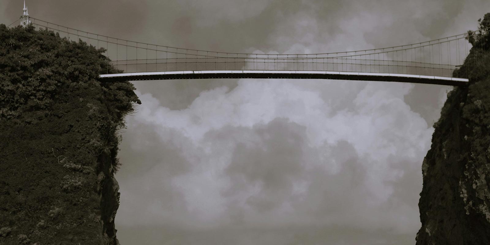 A bridge over a body of water under a cloudy sky.