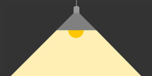 Simple gray ceiling lamp with a warm yellow glow illuminating a triangular area against a dark background