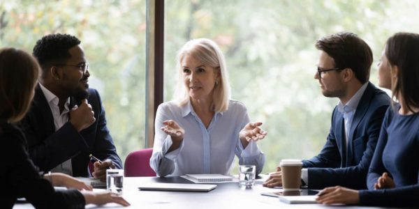 Group of professionals in a meeting discussing strategy with a senior woman leading the conversation