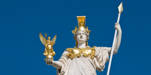 Close up of the Pallas Athena statue in Vienna holding a golden winged figure and spear with ornate gold armor against a clear blue sky