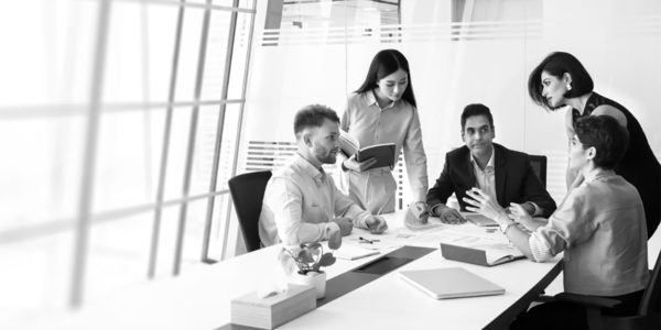 Business trainer presenting AI capability building for leaders to a group of professionals in a modern office setting with screen display